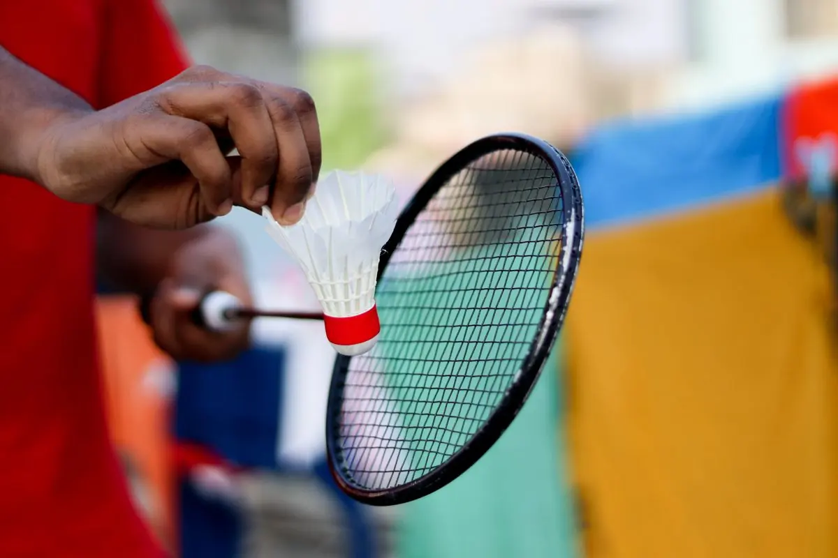Hand mit Federball und Badmintonschläger
