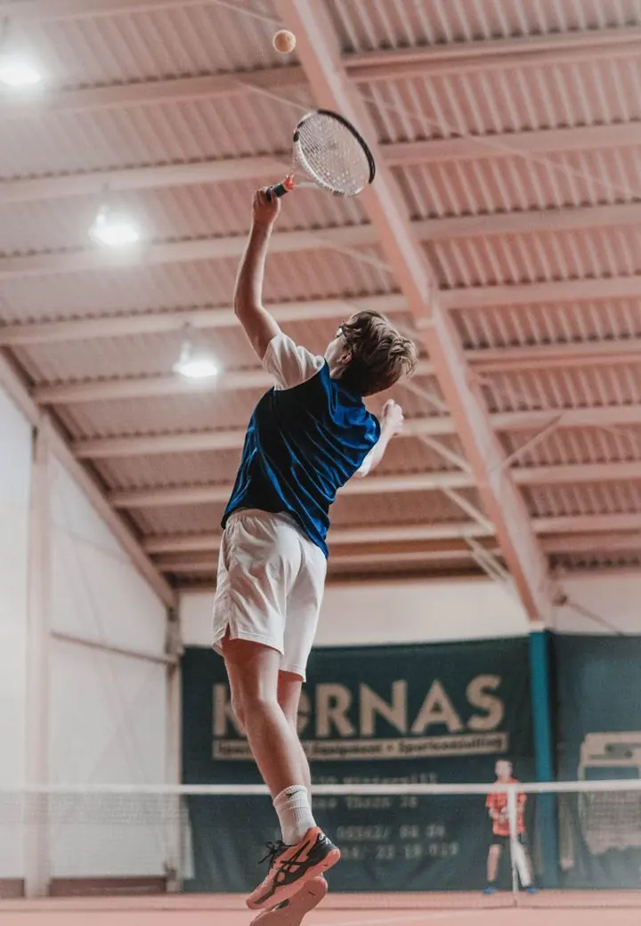 Tennisspieler beim Aufschlag in der Halle